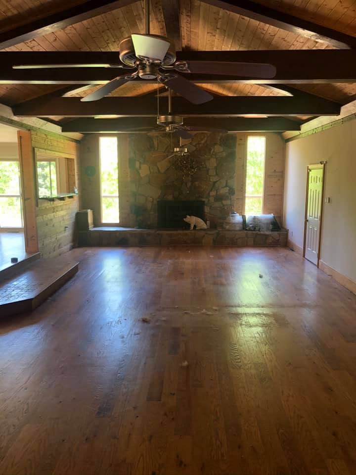Wide plank hardwood floor restored in a great room with vaulted beam ceiling
