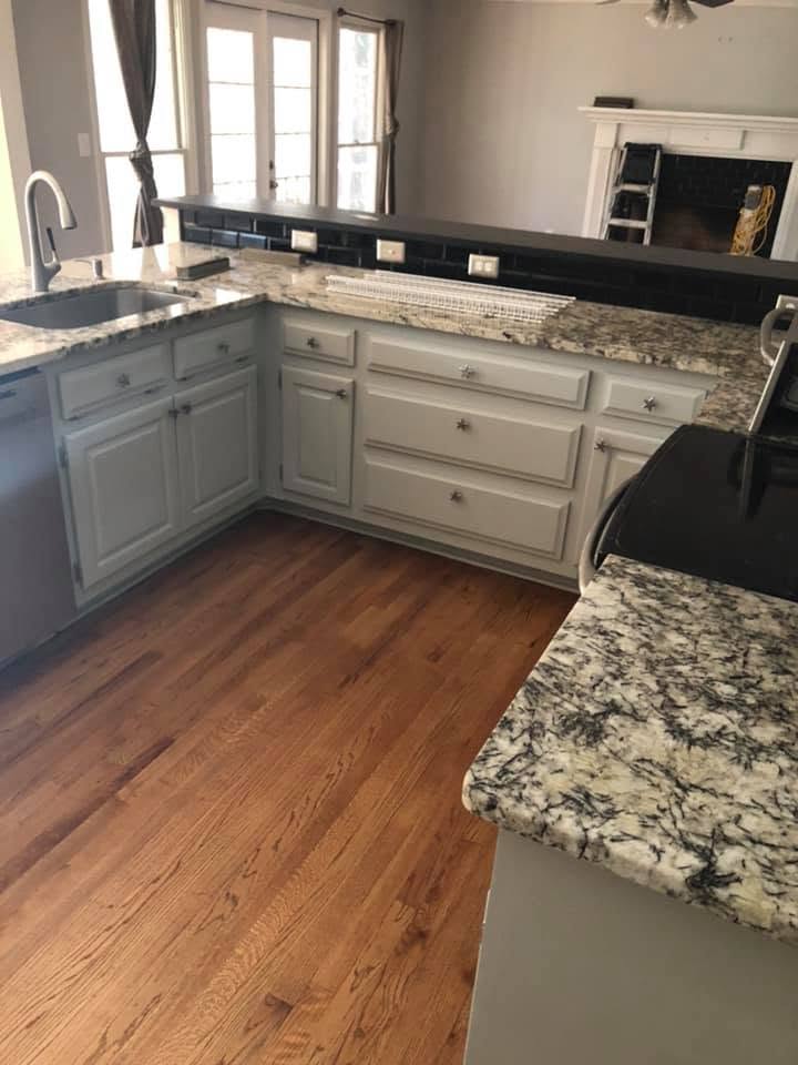 Refinished red oak kitchen floor beside painted cabinetry and granite counters